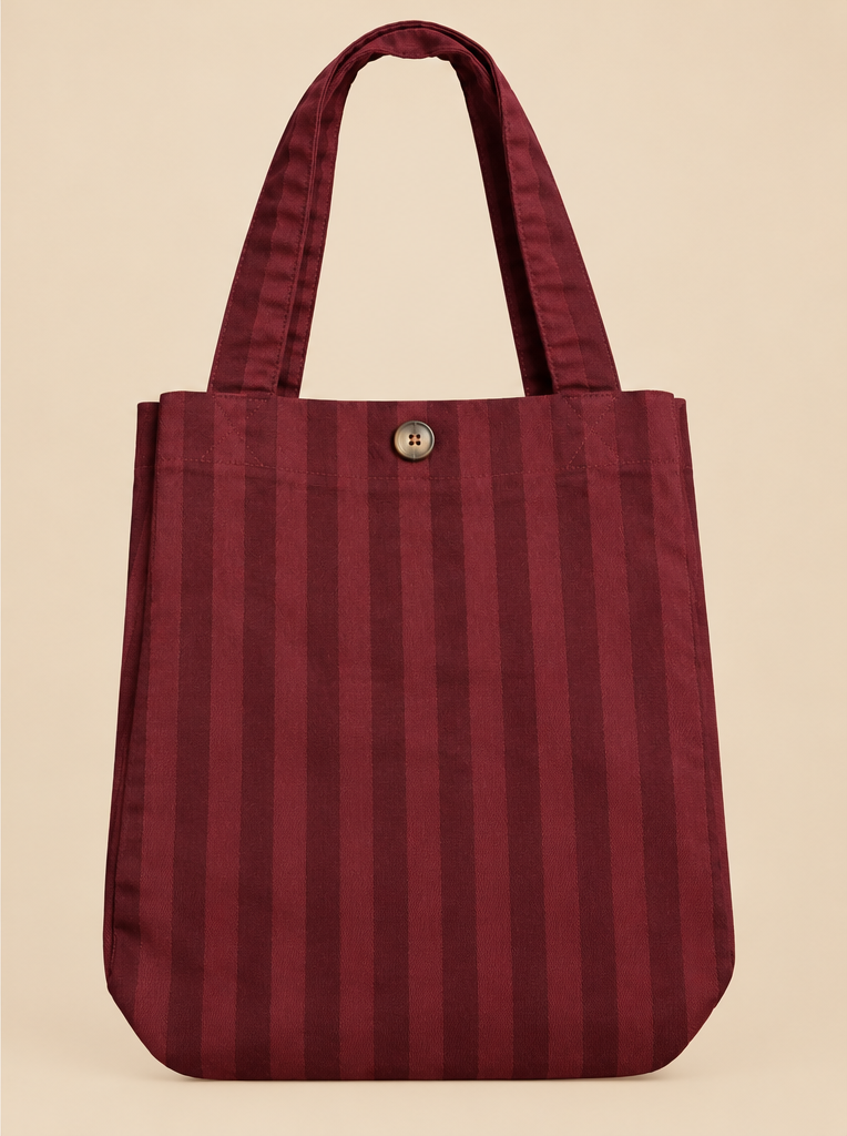 Bolso Lisboa tipo shopper burdeos con rayas verticales, asas largas y botón frontal sobre fondo beige
