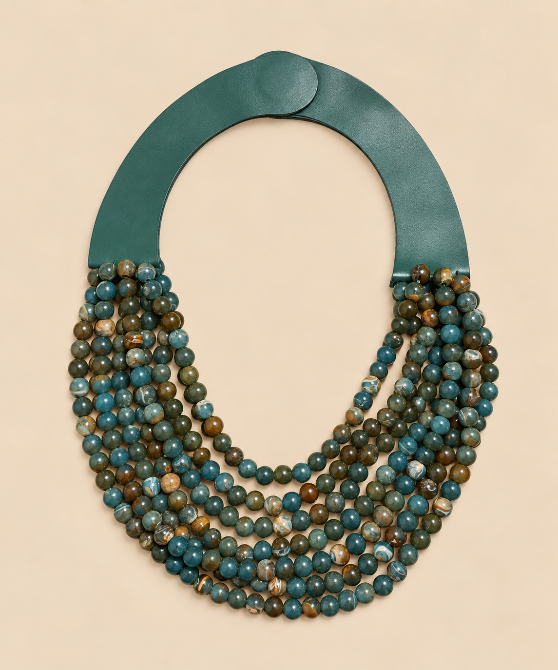 Collar Marrakech multicolor con pieza superior verde y cierre imantado sobre fondo beige